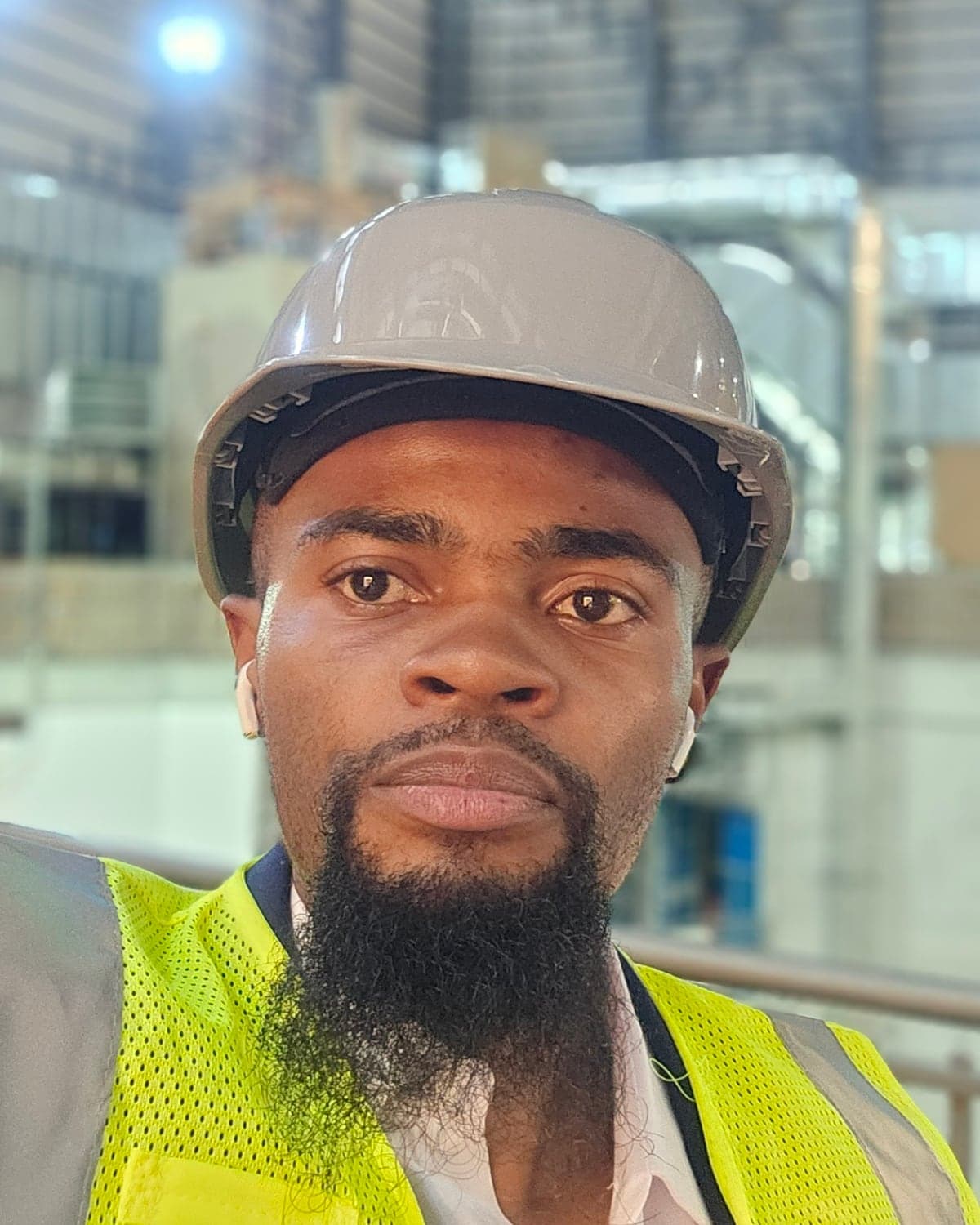 Samuel Ahana wearing a hard hat and a high-visibility vest inside an industrial hall.